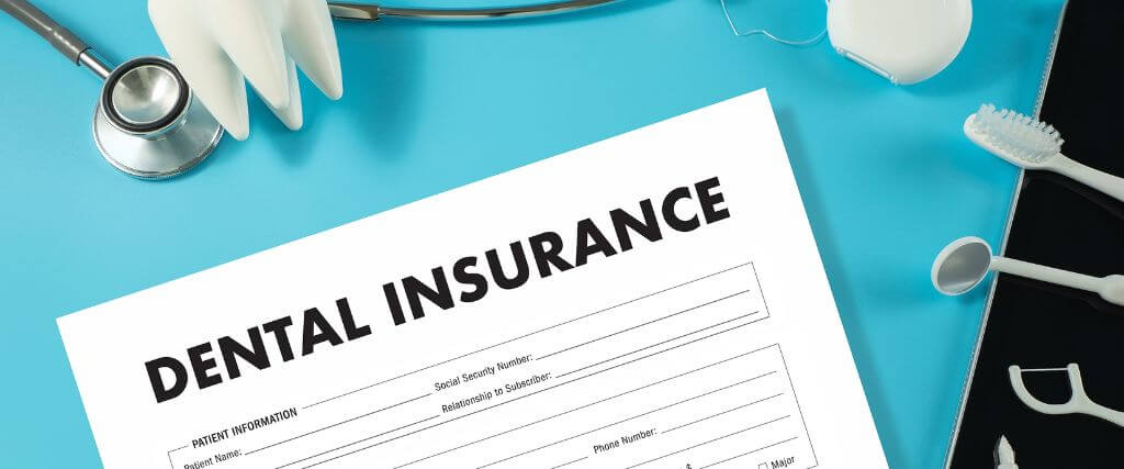 Dental insurance form on a clipboard surrounded by dental tools